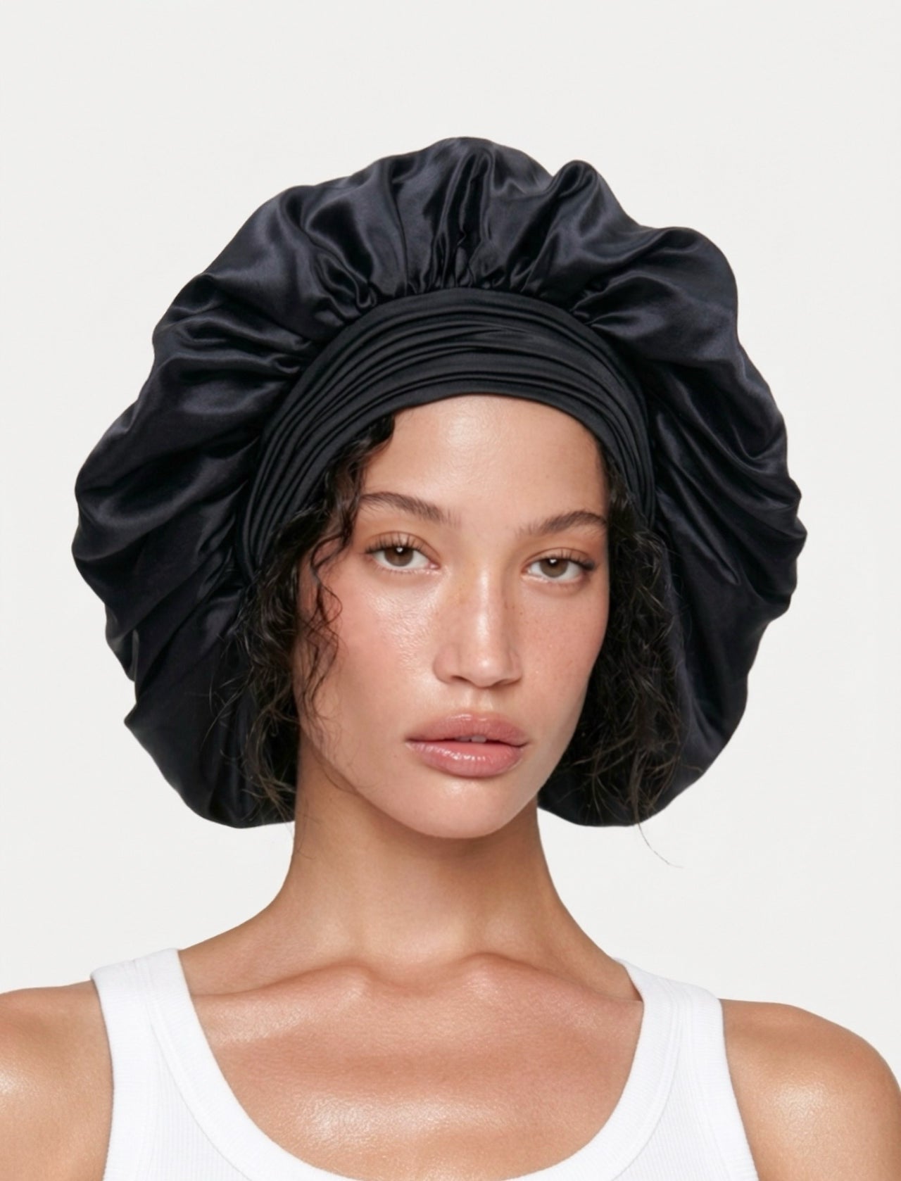 Model wearing a large black mulberry silk bonnet to protect her hair from frizz, damage, and breakage.
