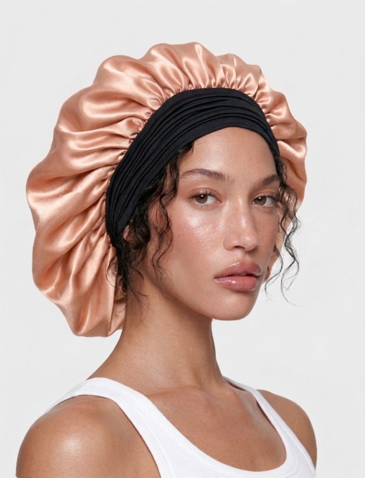 Model wearing a large black and pink mulberry silk bonnet to protect her hair from frizz, damage, and breakage.